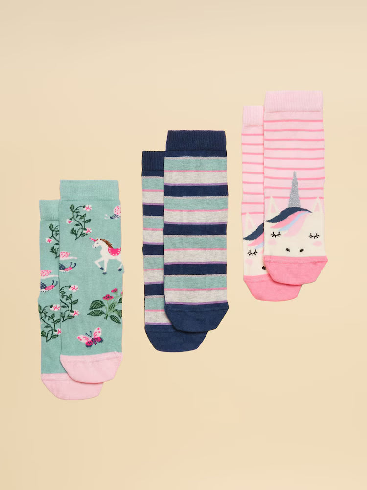 Set of three pairs of colorful socks with unicorn designs on a beige background