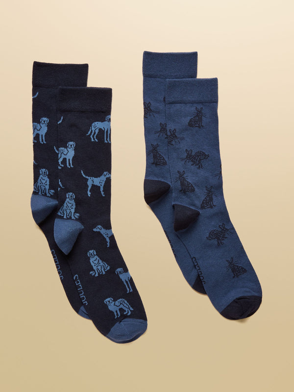 Two pairs of navy blue socks with dog patterns on a beige background