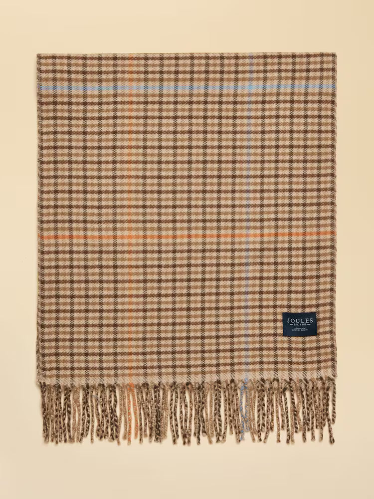 Plaid blanket with fringes and a brand label on a beige background