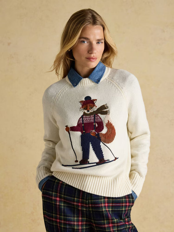 Woman wearing a sweater with a skiing bear design against a beige background