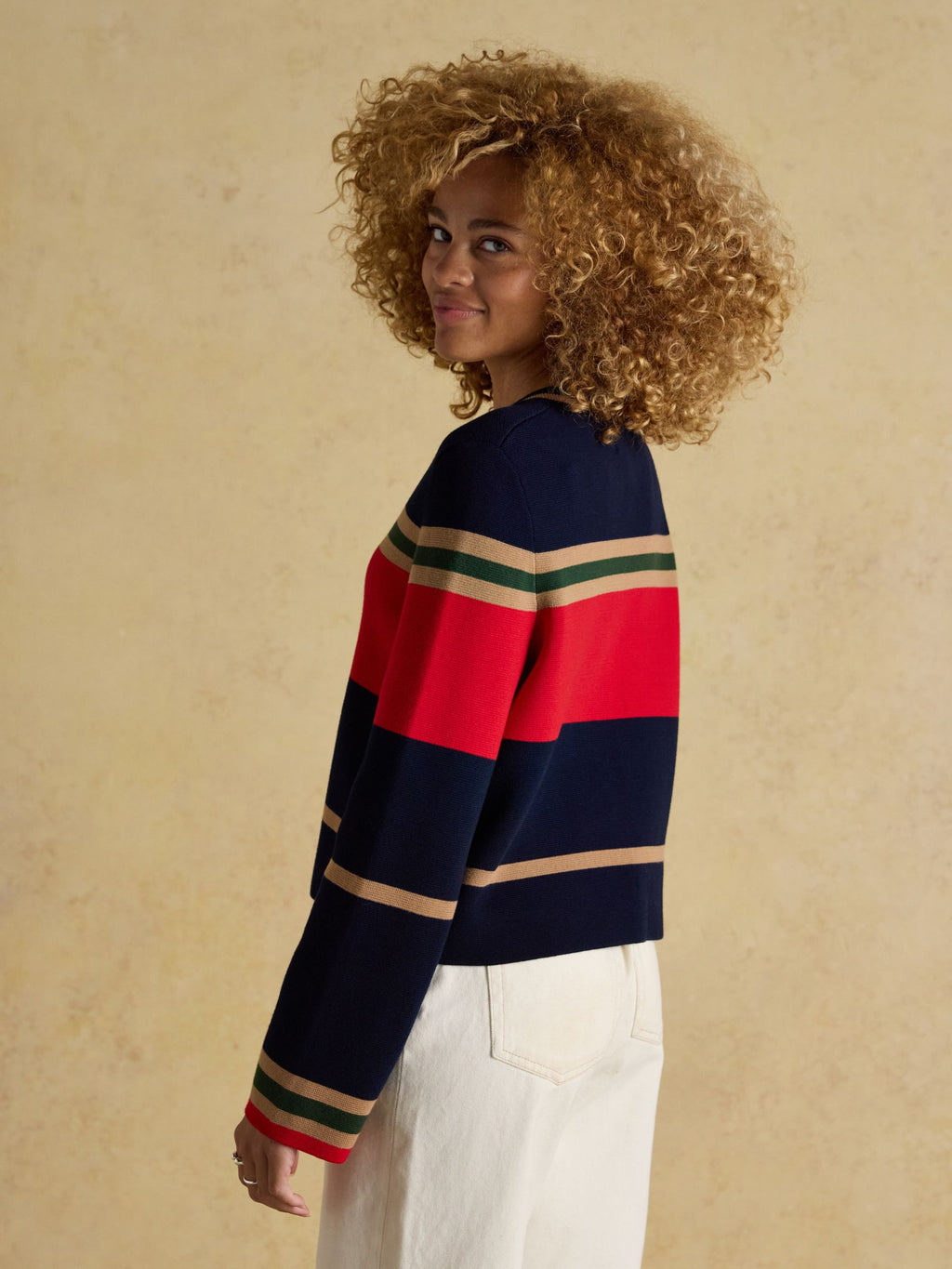 Person wearing a striped sweater with a beige background