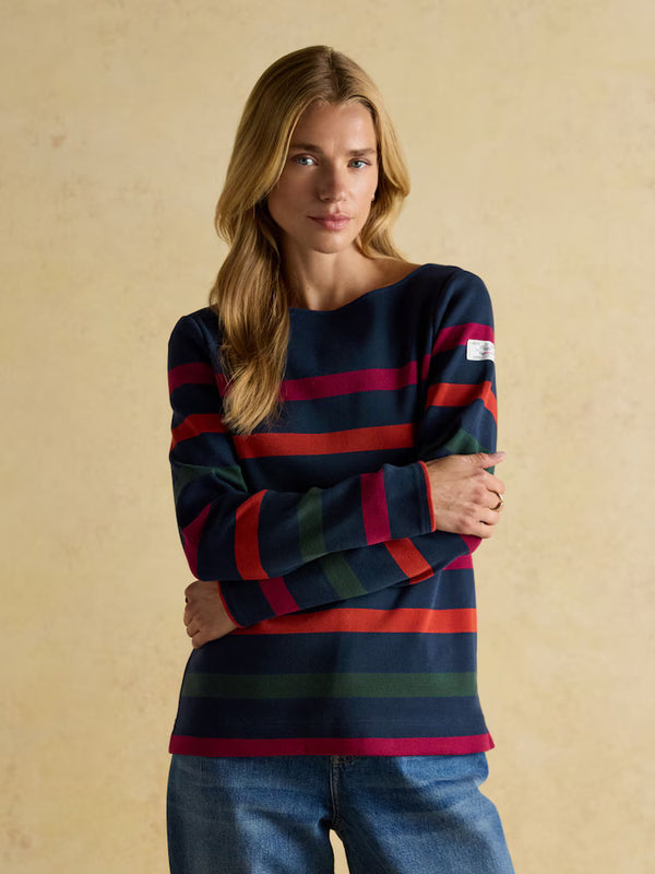 Woman wearing a navy sweater with red and green stripes against a beige background
