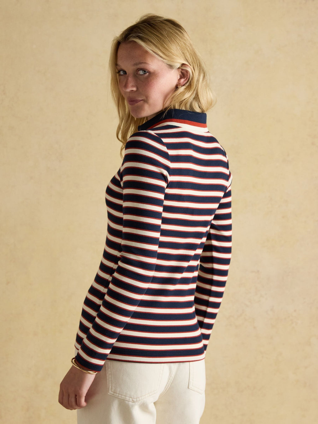 Woman wearing a striped sweater against a beige background