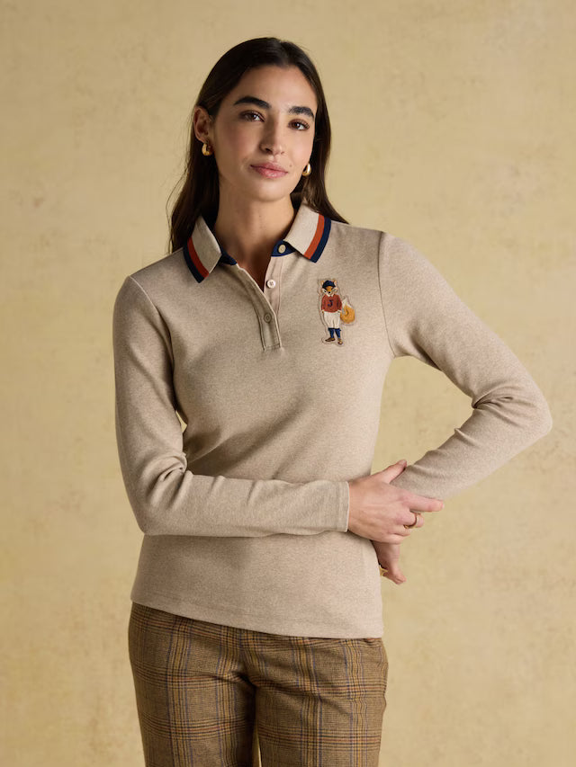 Woman wearing a beige long-sleeve polo shirt with a small embroidered design on a beige background