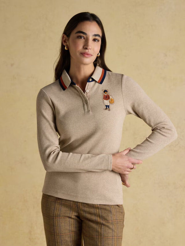 Woman wearing a beige long-sleeve polo shirt with a small embroidered design on a beige background