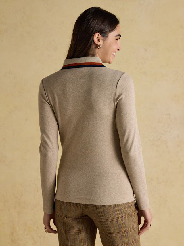 Woman wearing a beige sweater with a striped collar against a beige background