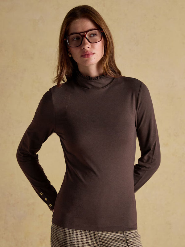 Woman wearing a brown turtleneck sweater against a beige background