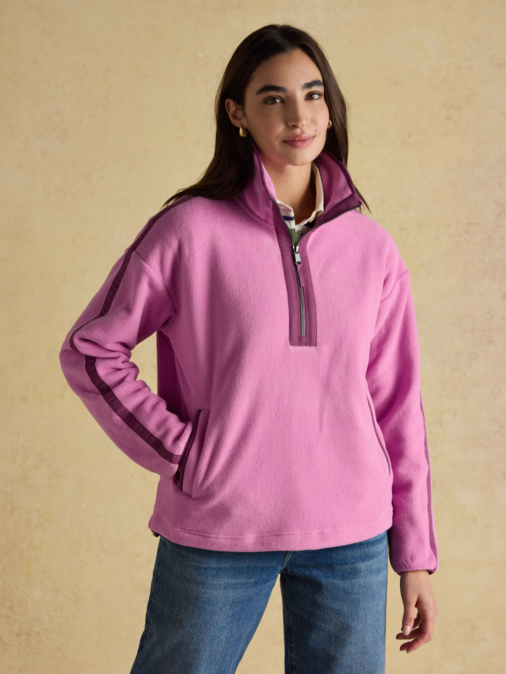 Woman wearing a pink fleece pullover against a beige background