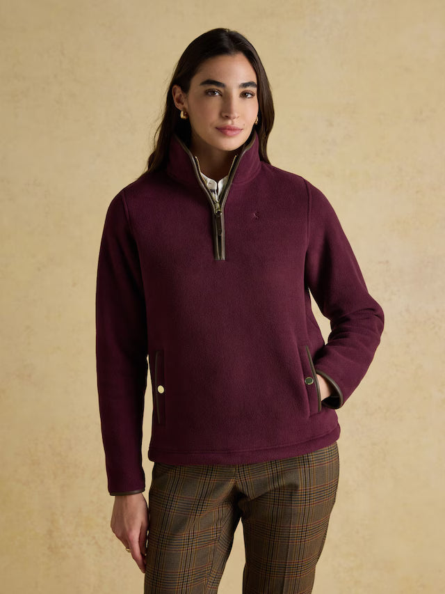 Woman wearing a purple fleece pullover against a beige background