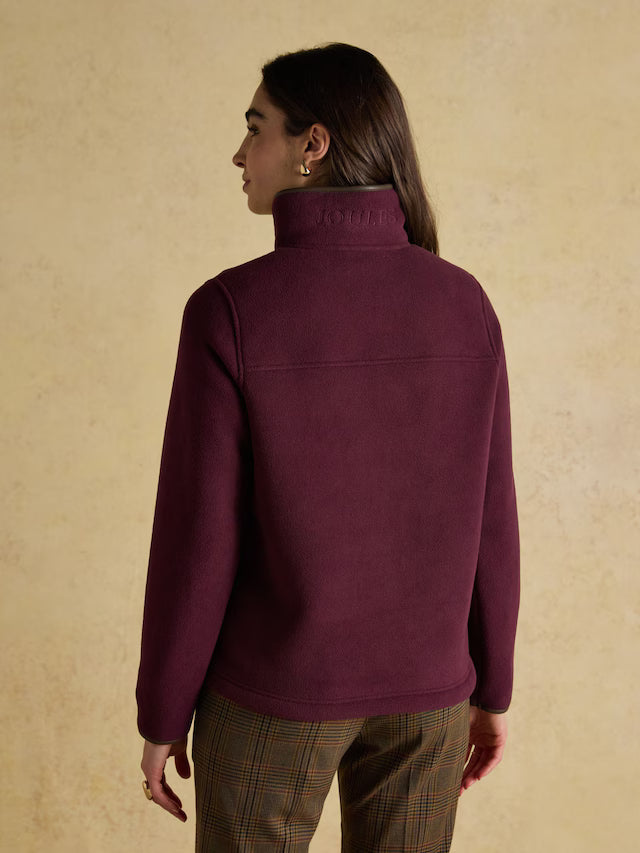 Person wearing a purple jacket with a brand logo on a beige background