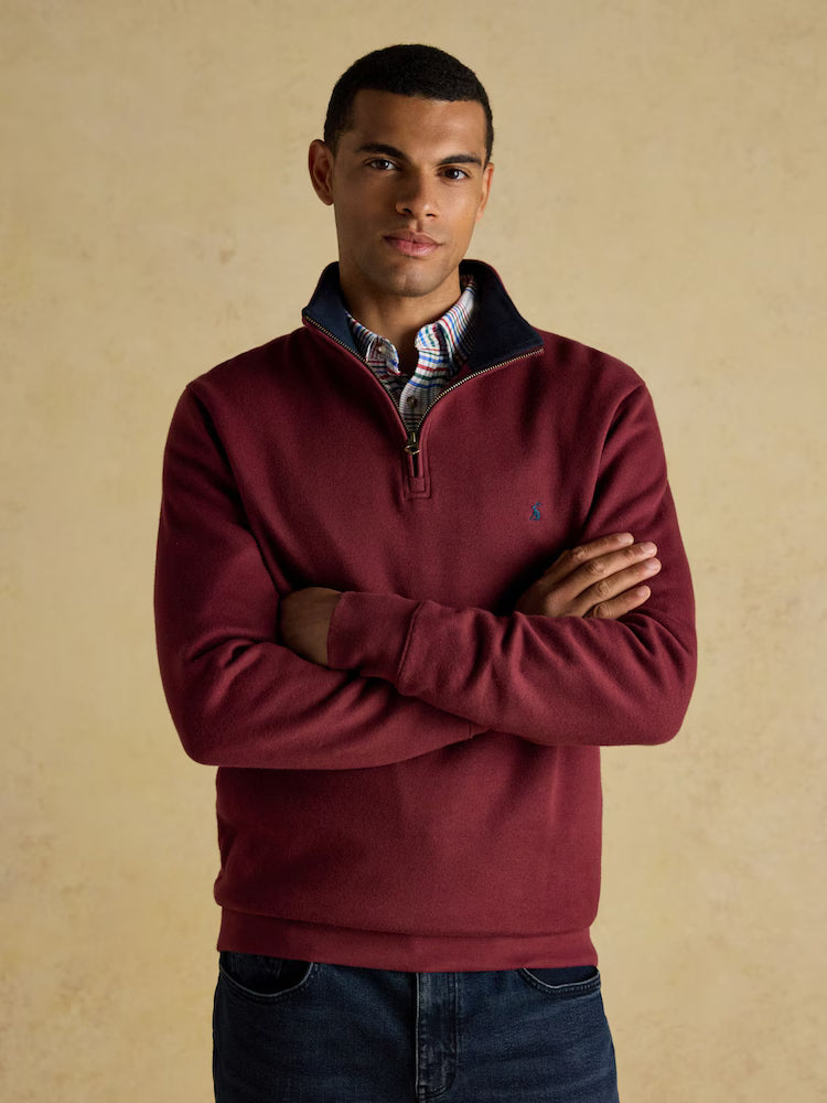 Man wearing a burgundy sweater with a beige background