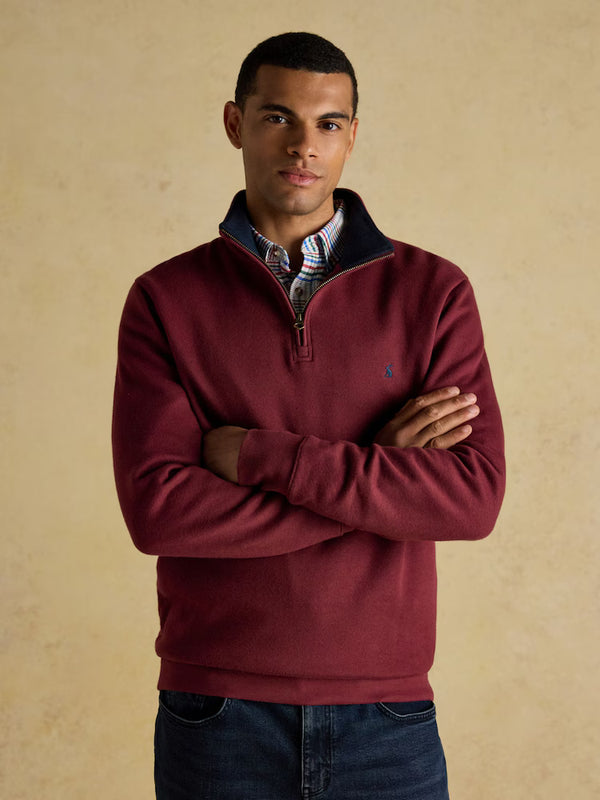Man wearing a burgundy sweater with a beige background