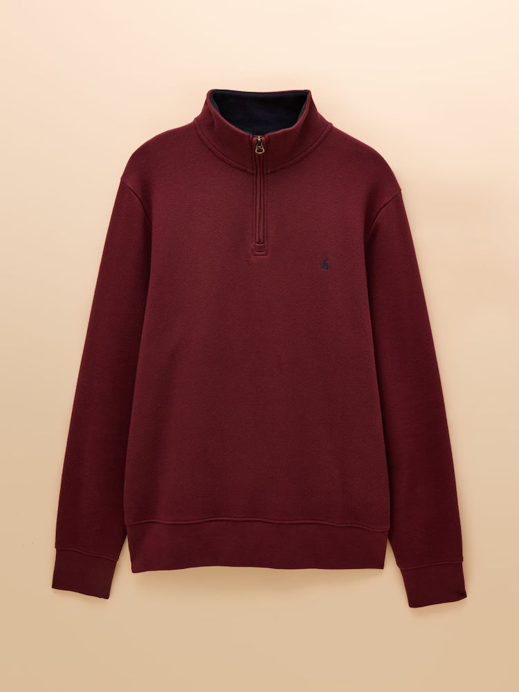 Maroon sweatshirt with a small logo on a beige background