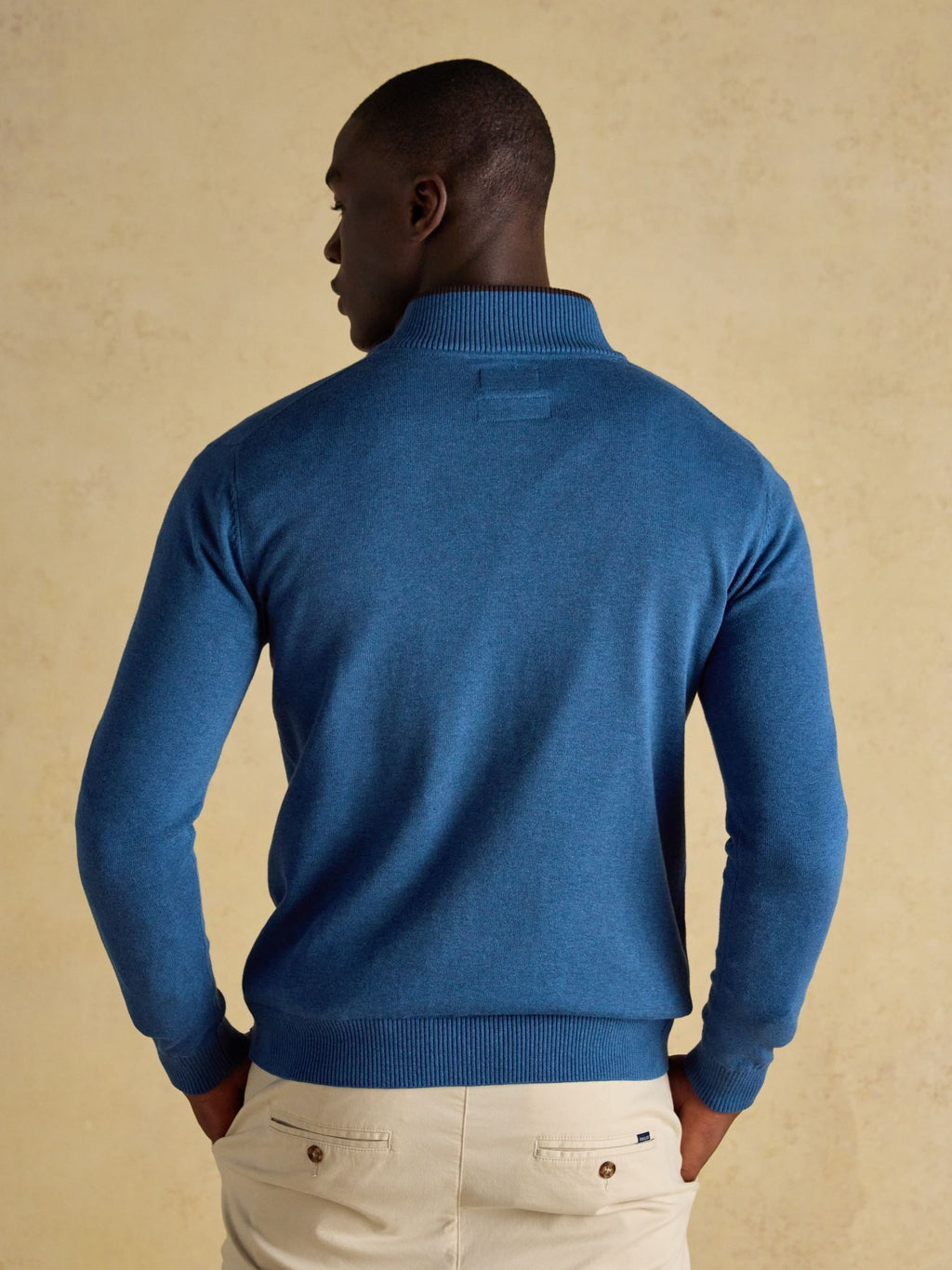 Man wearing a blue sweater against a beige background