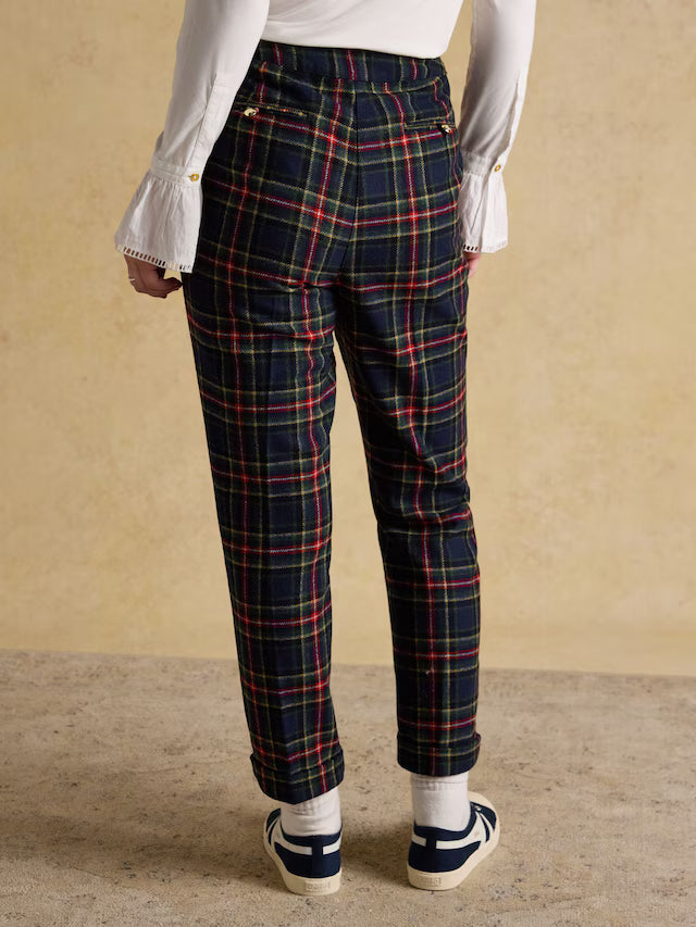 Person wearing navy plaid pants with a beige background