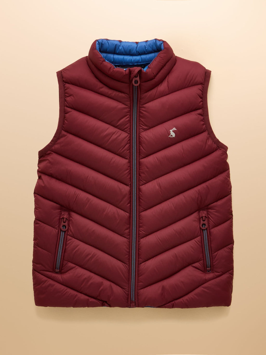 Red puffer vest with blue lining on a beige background