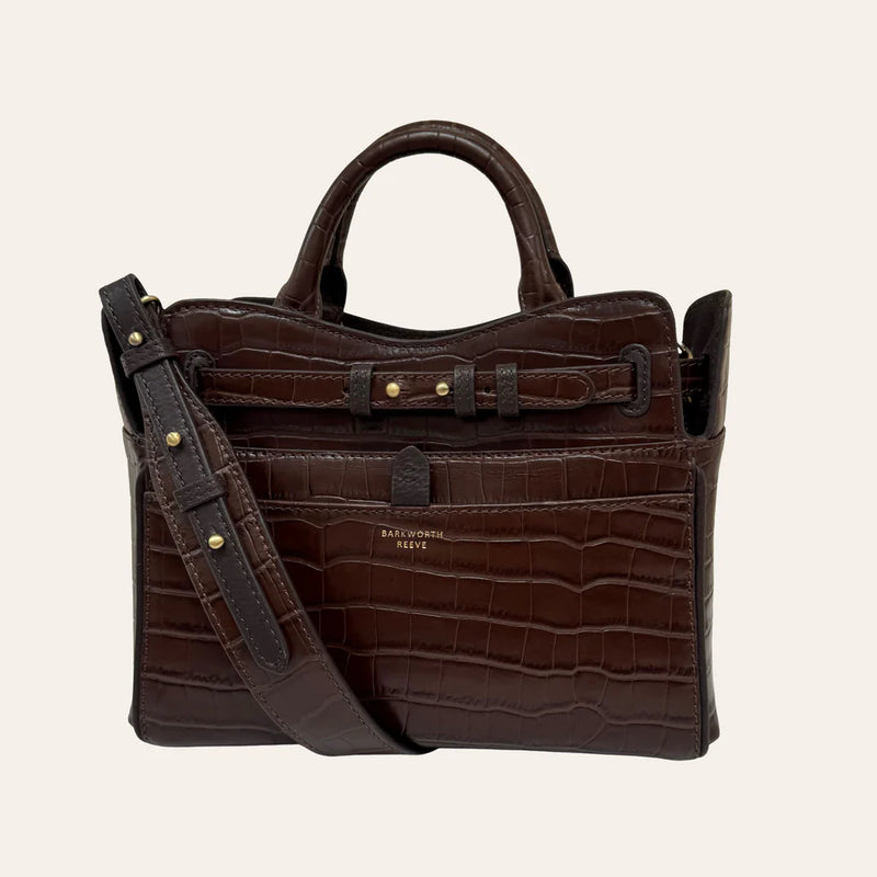 Brown leather handbag with a strap on a beige background