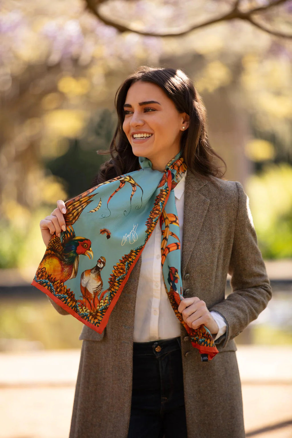 Woman holding a colorful scarf with nature-themed design outdoors