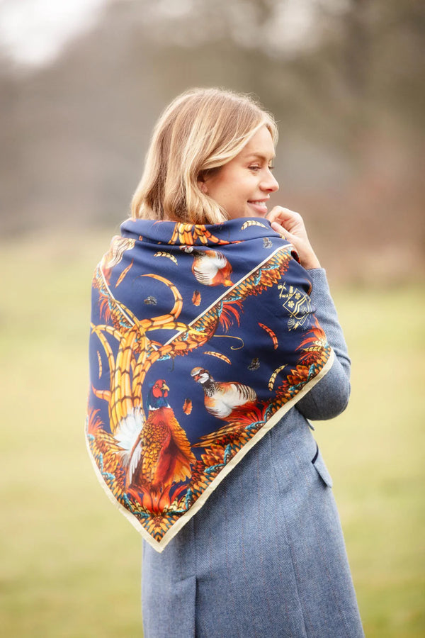 Woman wearing a blue scarf with a nature-themed design in an outdoor setting