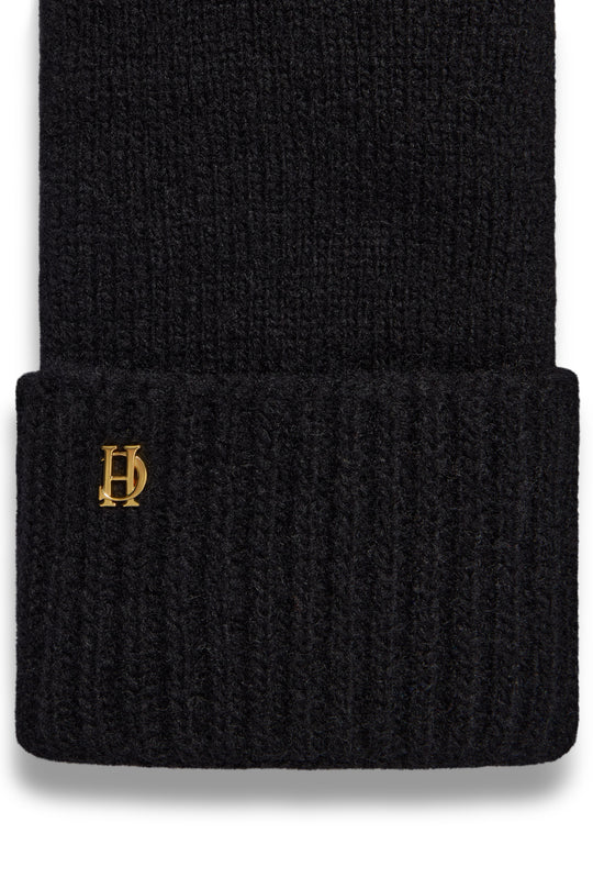 Black knit beanie with a gold logo on a white background