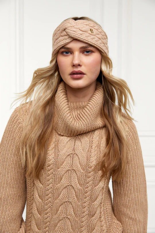 Woman wearing a beige knit sweater and headband against a white background