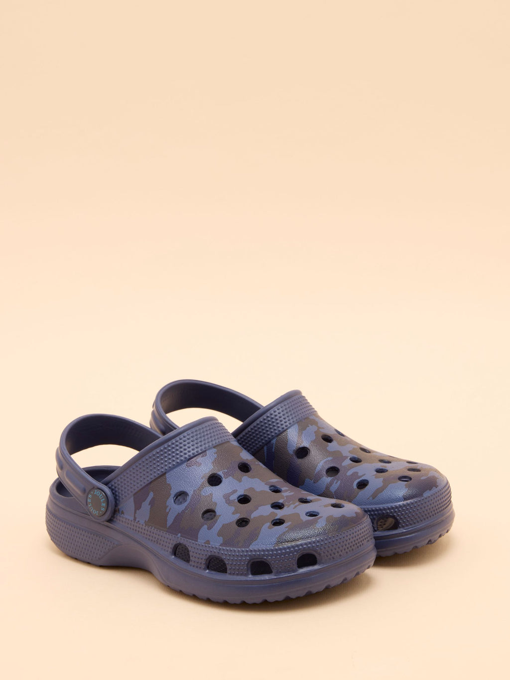 Pair of navy blue clogs with camouflage pattern on a beige background