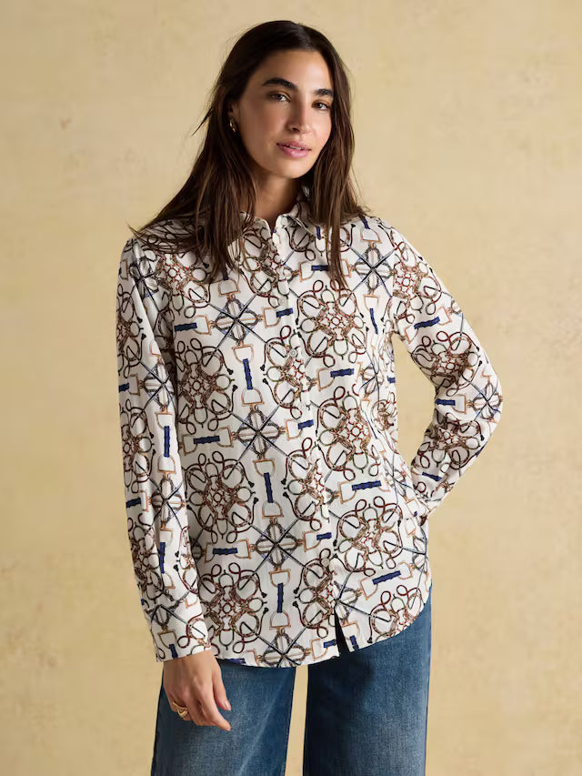 Woman wearing a patterned shirt and jeans against a beige background