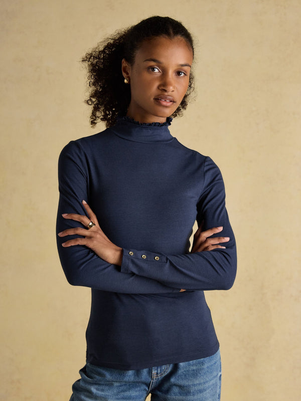 Woman wearing a navy blue long-sleeve top with a beige background