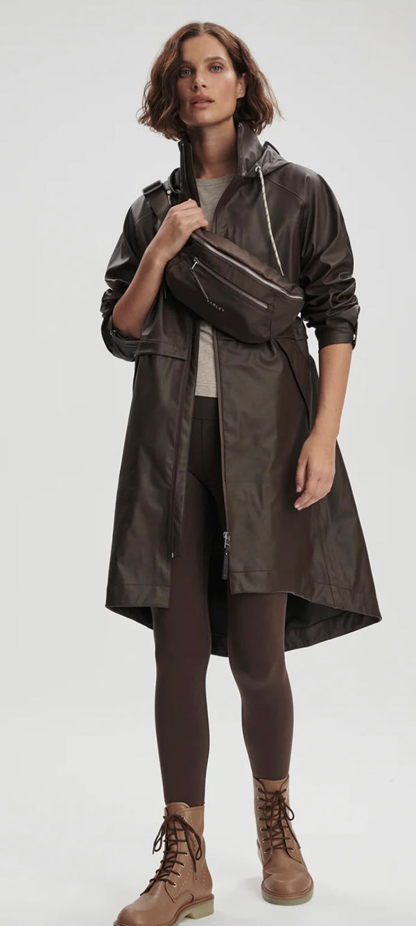 Woman wearing a dark raincoat with a hood on a white background