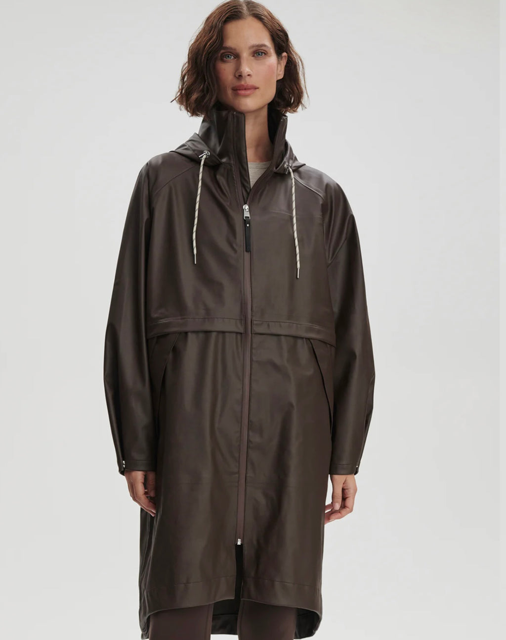 Woman wearing a long brown raincoat on a white background