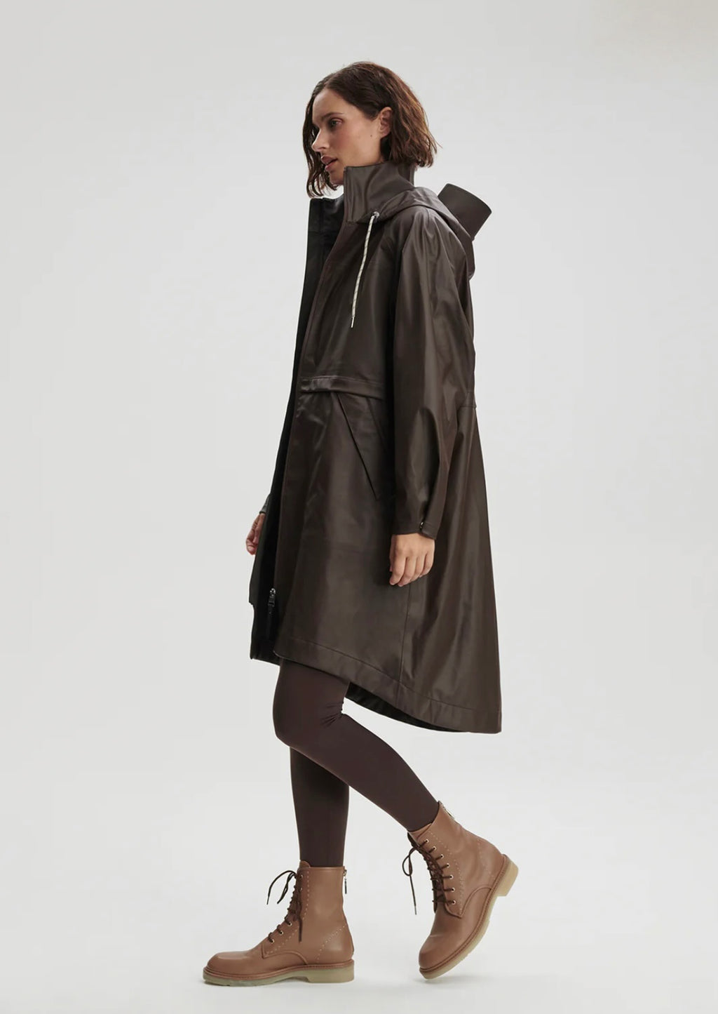 Woman wearing a dark raincoat on a white background