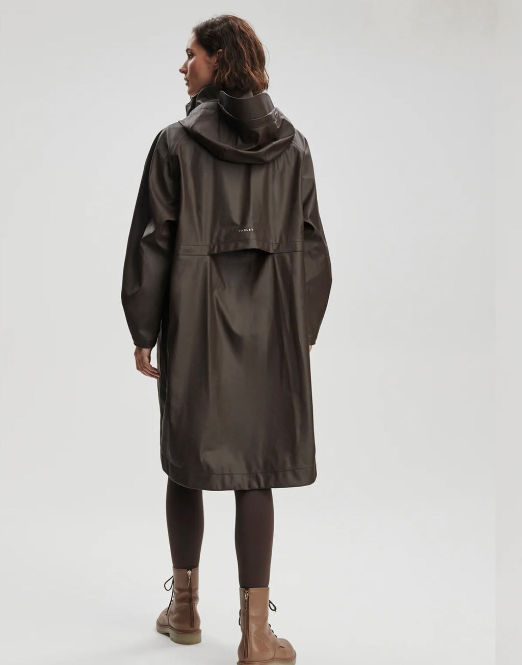 Person wearing a long dark coat on a white background