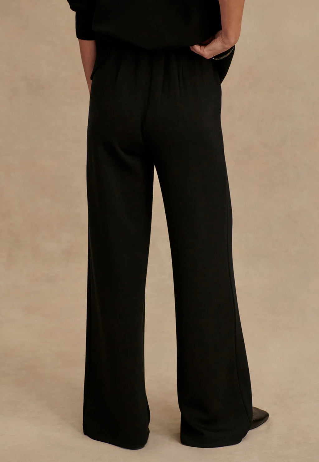 Black wide-leg pants worn by a person on a beige background