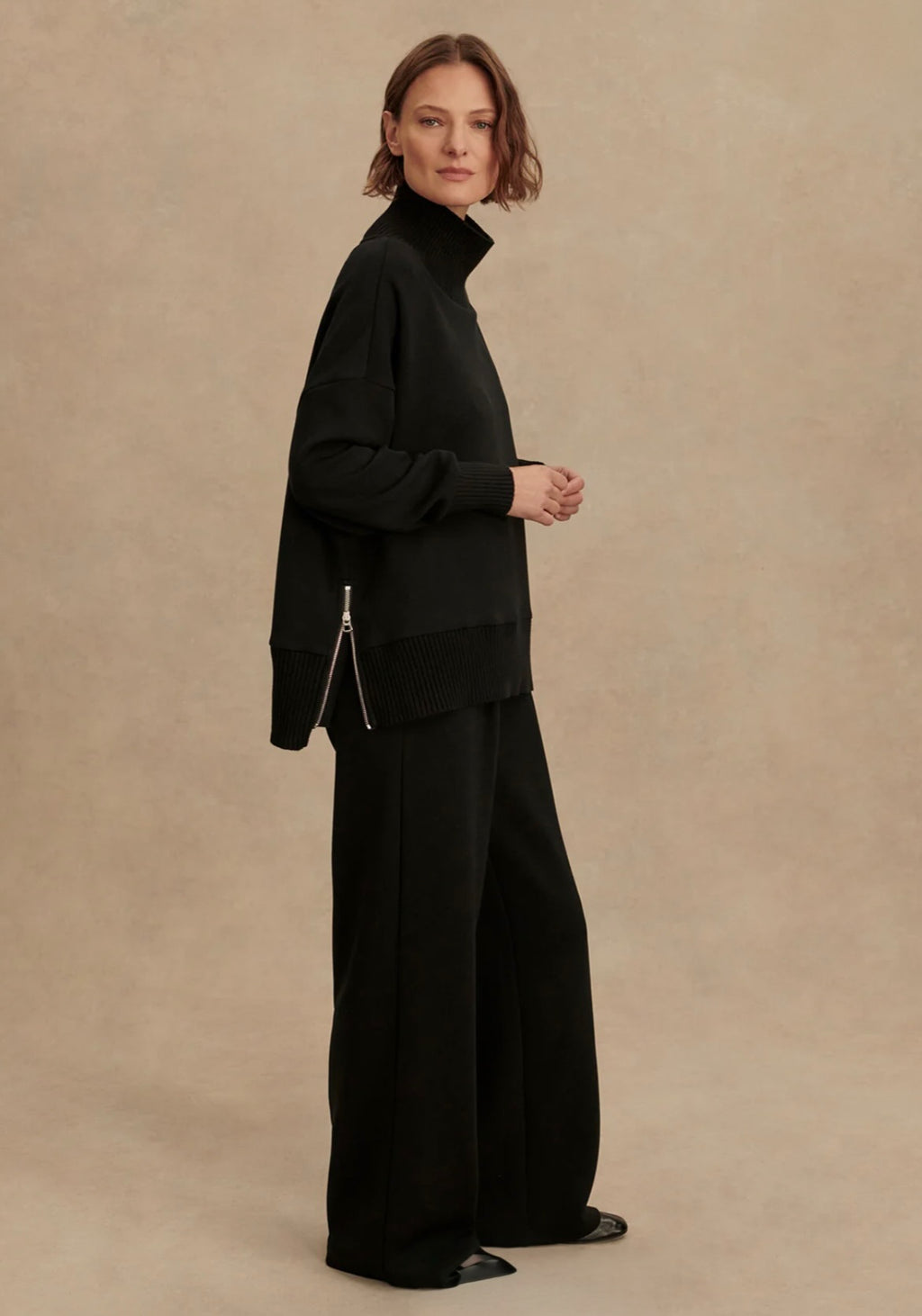 Person wearing a black outfit on a beige background