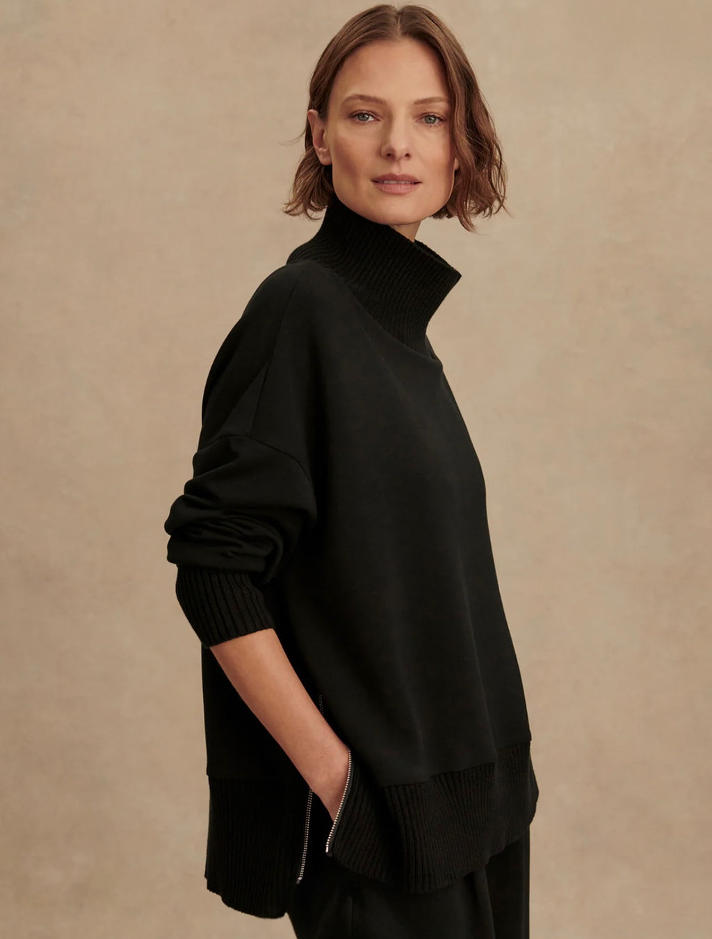 Woman wearing a black turtleneck sweater against a beige background