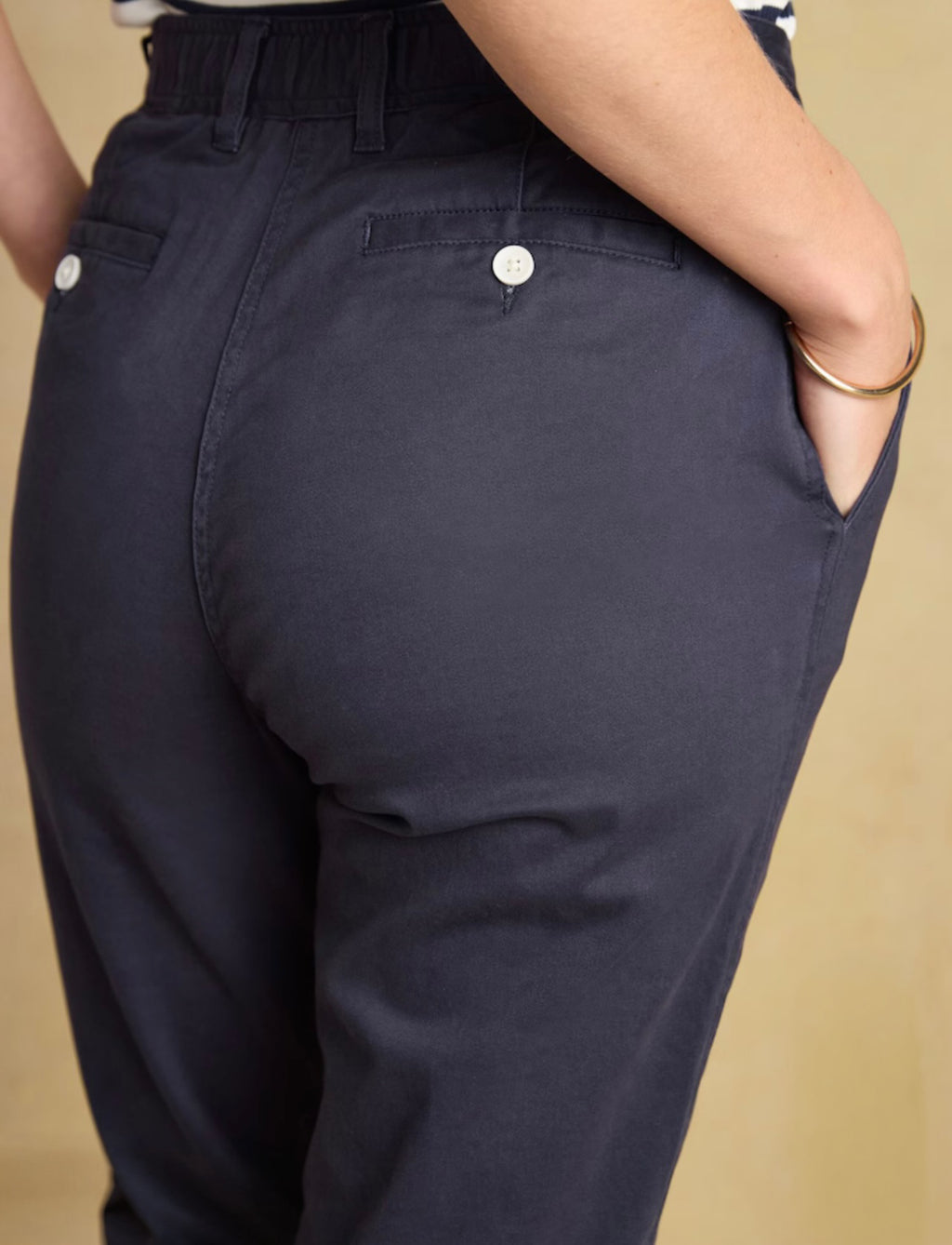 Navy blue pants with white buttons on a beige background