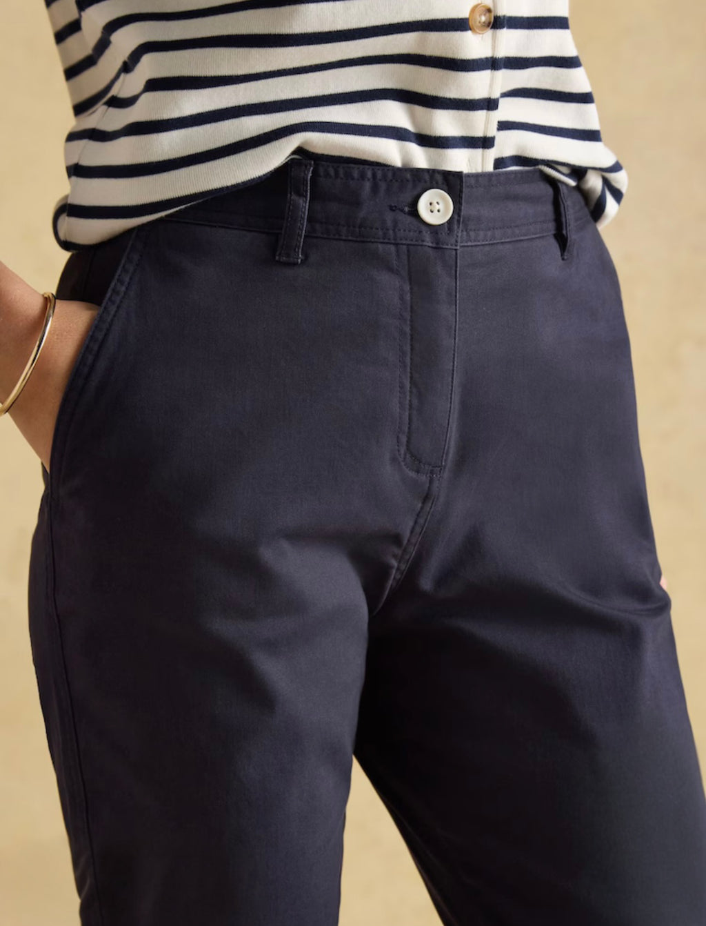 Navy pants worn with a striped shirt on a beige background