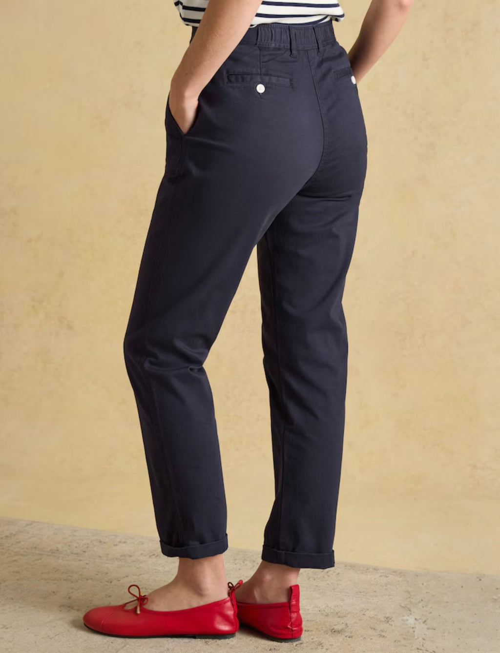 Person wearing navy pants with a beige background