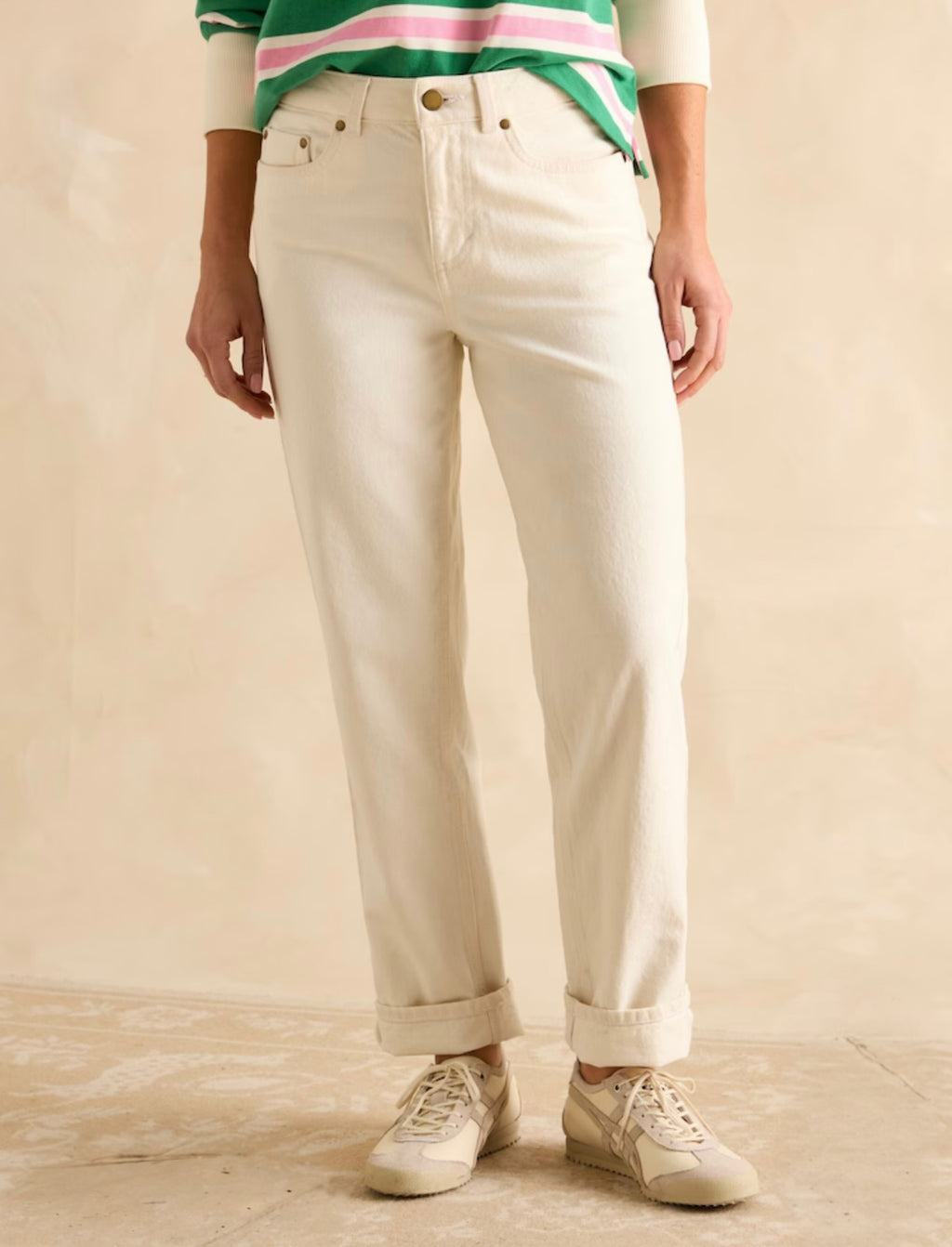 Person wearing cream trousers on a beige background