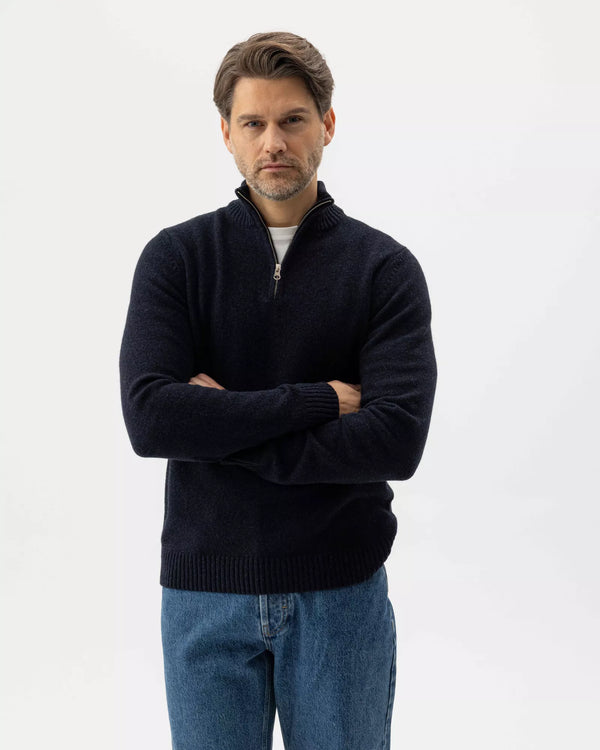 Man wearing a dark blue sweater and jeans on a white background