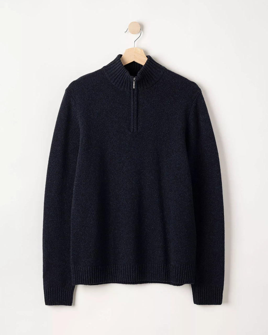 Navy sweater on a hanger against a white background