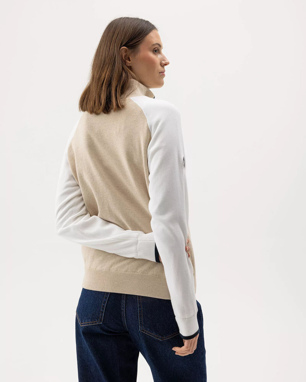 Woman wearing a beige and white pullover with a zipper on a white background