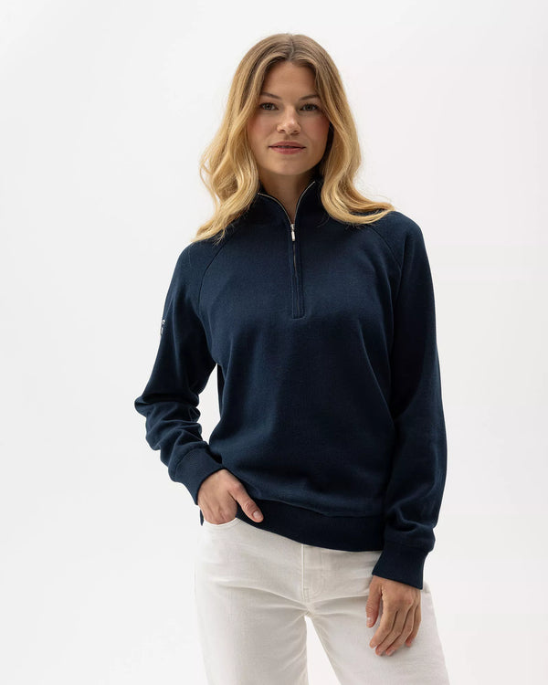 Woman wearing a navy blue half-zip sweatshirt against a white background