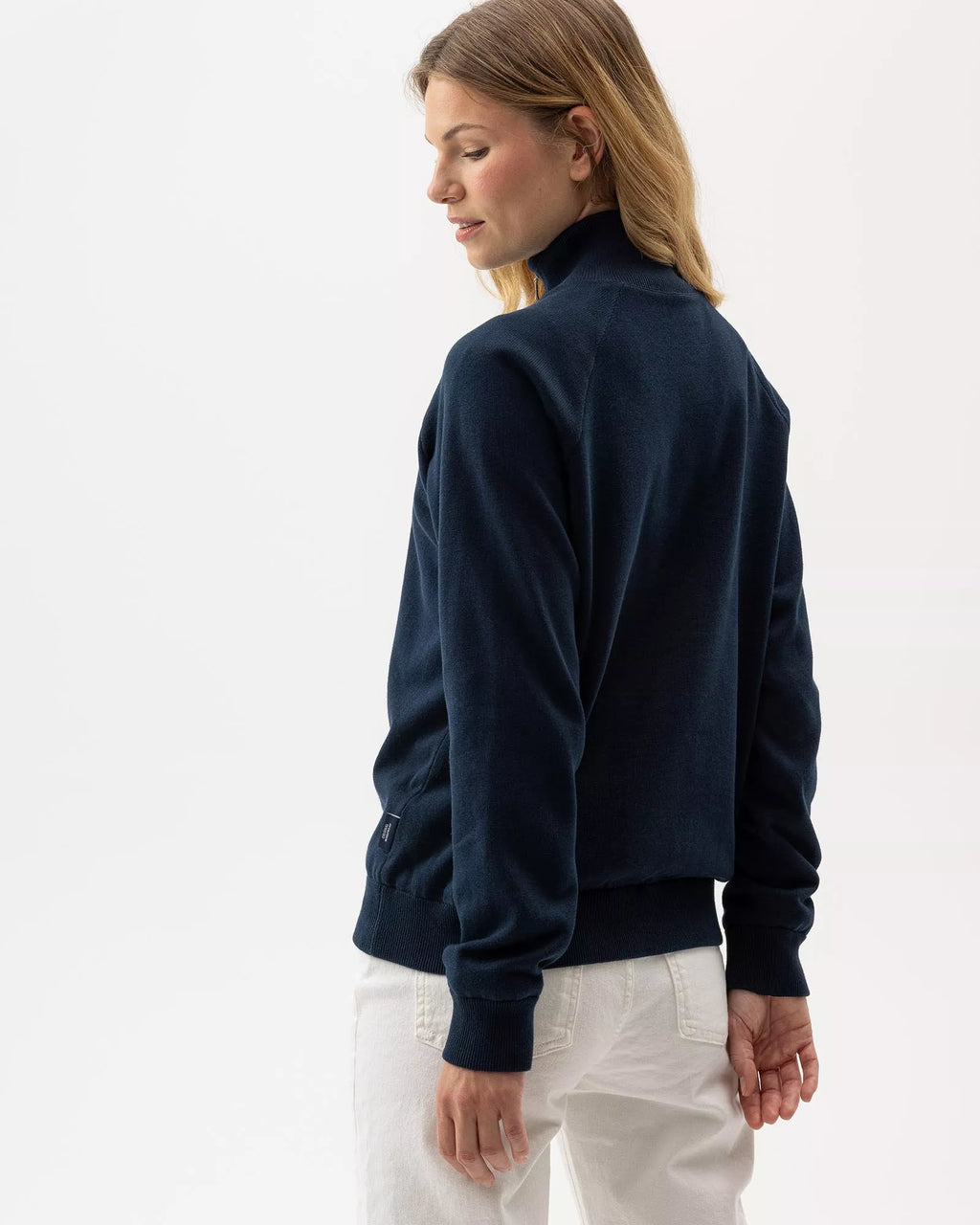 Woman wearing a navy blue half-zip sweatshirt against a white background