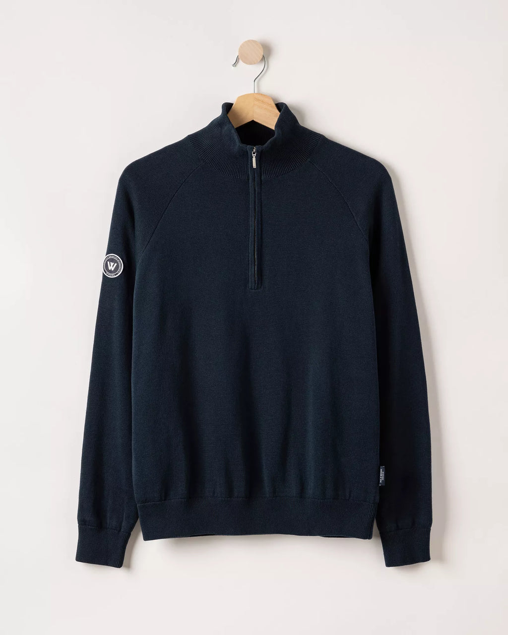 Navy blue half-zip sweatshirt on a hanger against a white background