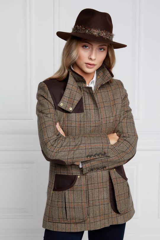 Woman wearing a plaid coat and hat against a white background