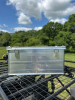 Clear plastic container on a bike rack with a scenic background of trees and blue sky.