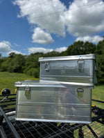 Metal toolbox on a grassy area with a blue sky and clouds in the background