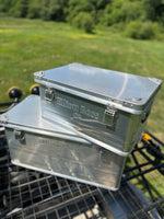 Metal toolbox on a motorcycle with a grassy field in the background