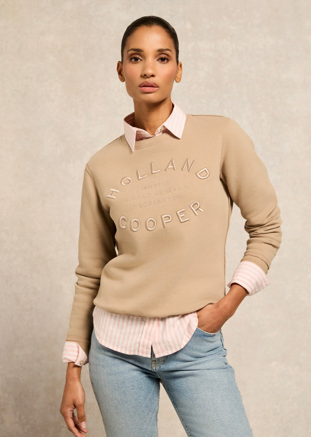 Woman wearing a beige sweater with 'Holland Cooper' branding on a neutral background